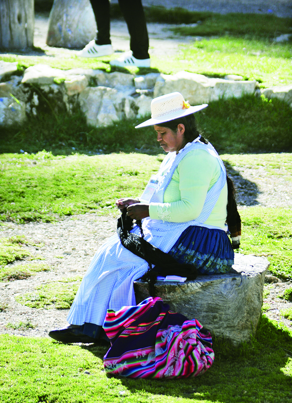 햇빛 아래에서 뜨개질을 하고 있는 볼리비아 여인
