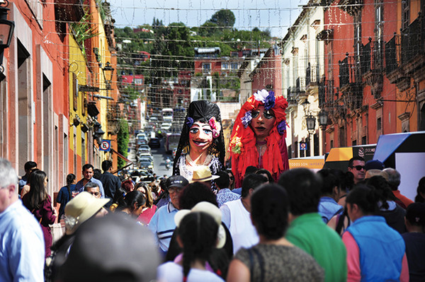 여행자들 위로 우뚝 솟아있는 거대 인형들