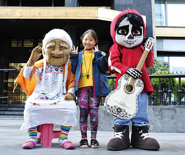 코코할머니와 미구엘 사이에서 행복한 아이가호루라기 목걸이를 하고 있다