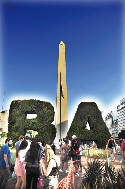 오벨리스코와 부에노스아이레스를 상징하는 나무 조형물을 배경으로 사진을 찍기 위해 기다리는 여행자들