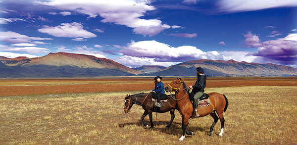 초원에서 말을 타며 가우초와 대화를 즐기는 아이