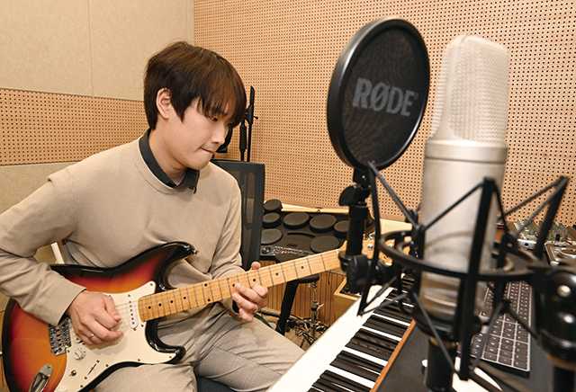 건반 앞에서 기타 연주를 하며 곡을 만들고 있는 오동진씨